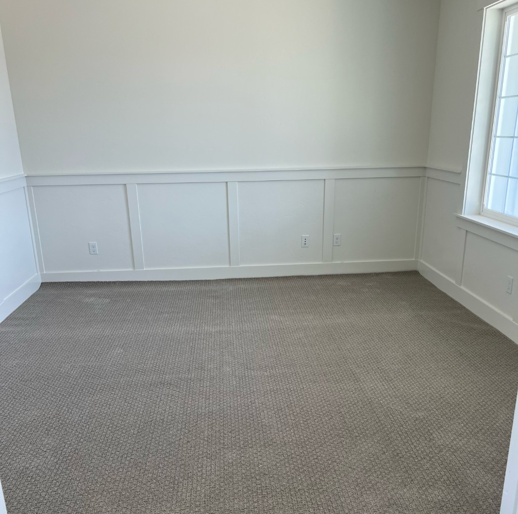 Professional carpet installation with light grey patterned carpet and white wainscoting