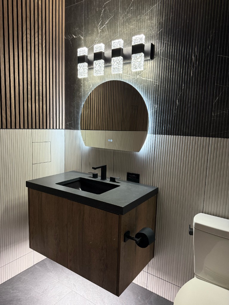 Contemporary bathroom with floating wood vanity, fluted marble walls, and backlit circular mirror