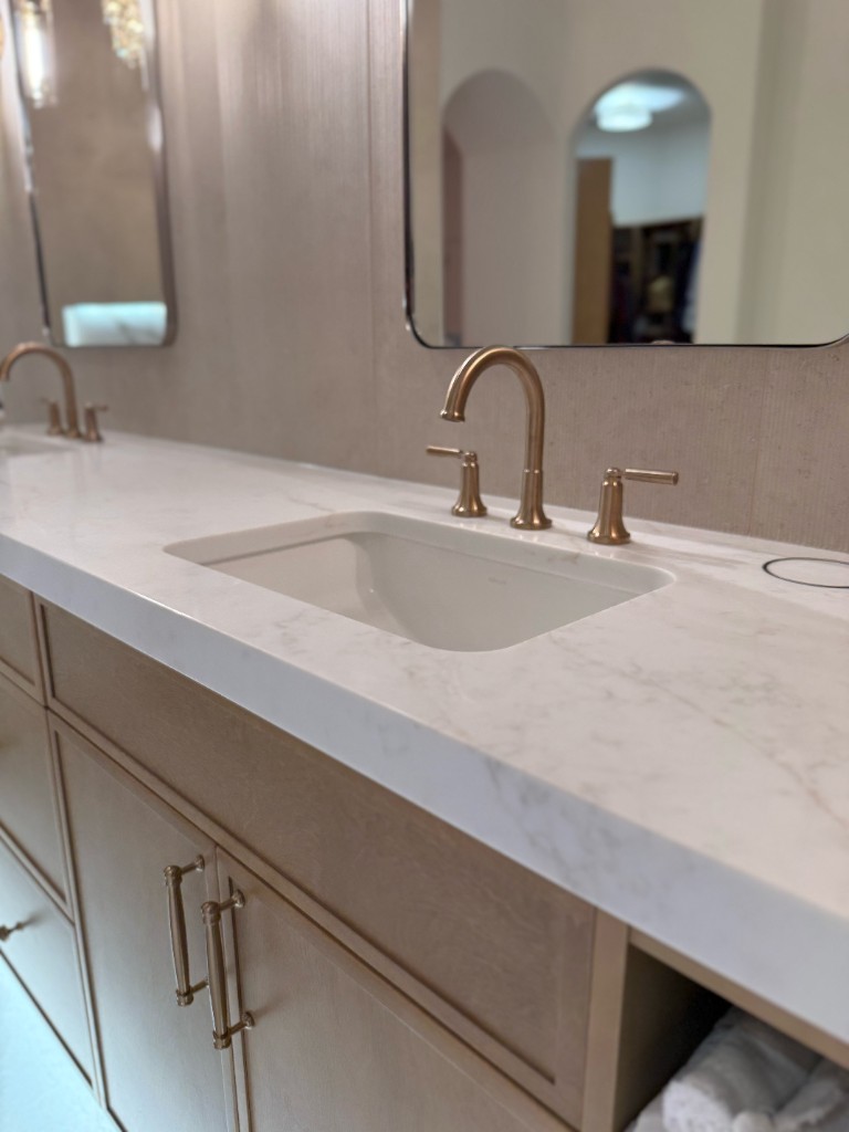 Bathroom vanity with white marble countertops and brushed gold fixtures