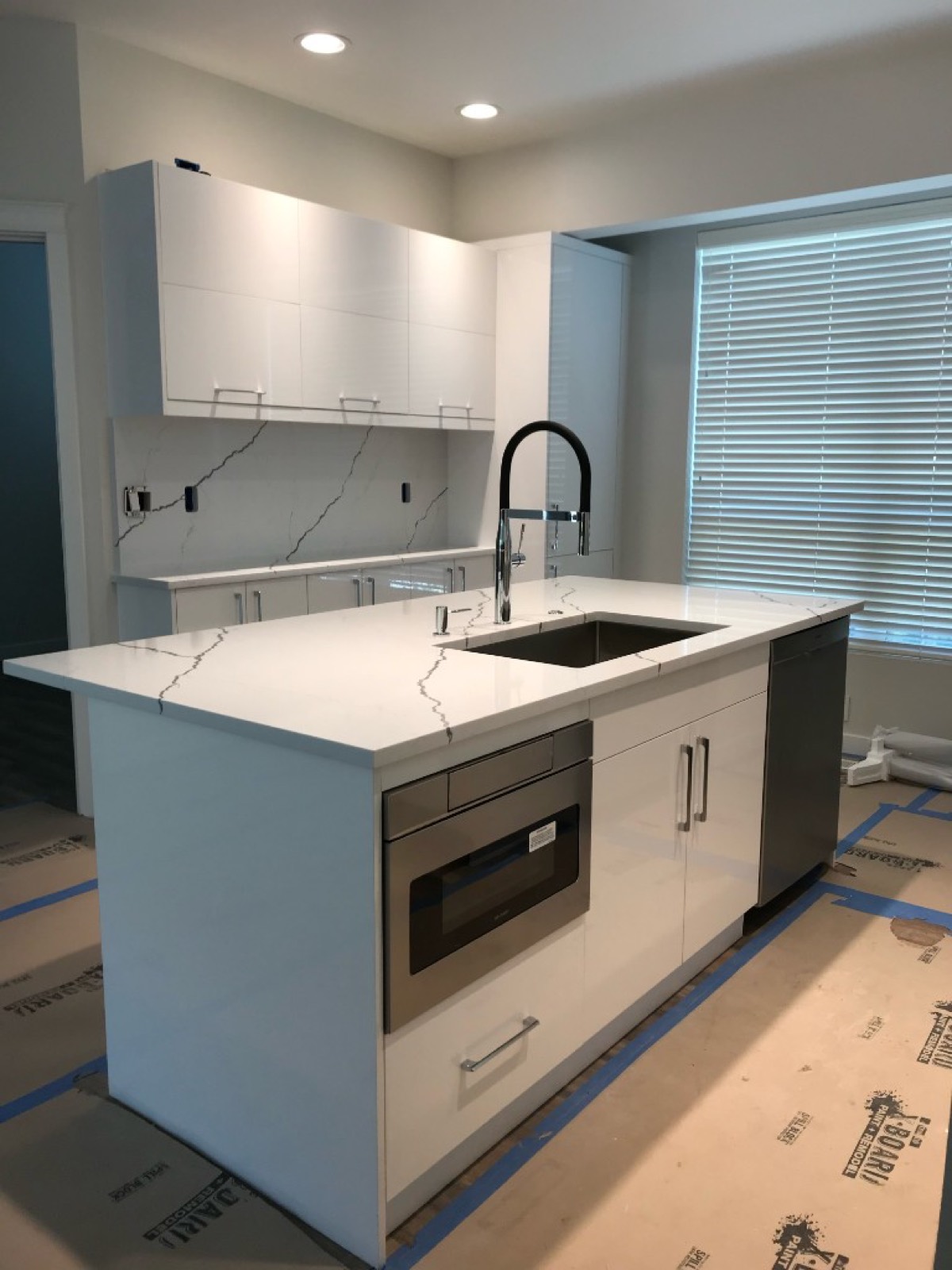 Modern kitchen remodel with white island, marble-look quartz countertops, and stainless appliances