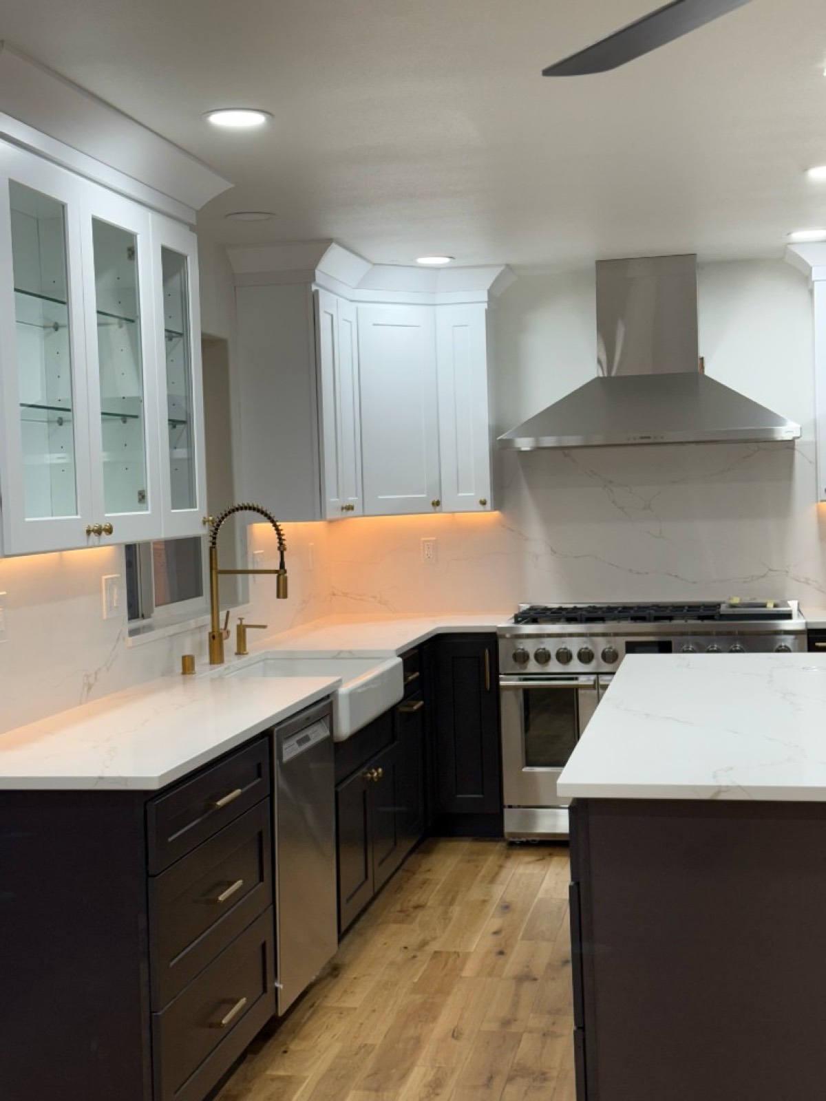 Two-tone kitchen remodel with navy lower cabinets, white upper cabinets, brass hardware, and marble-look surfaces